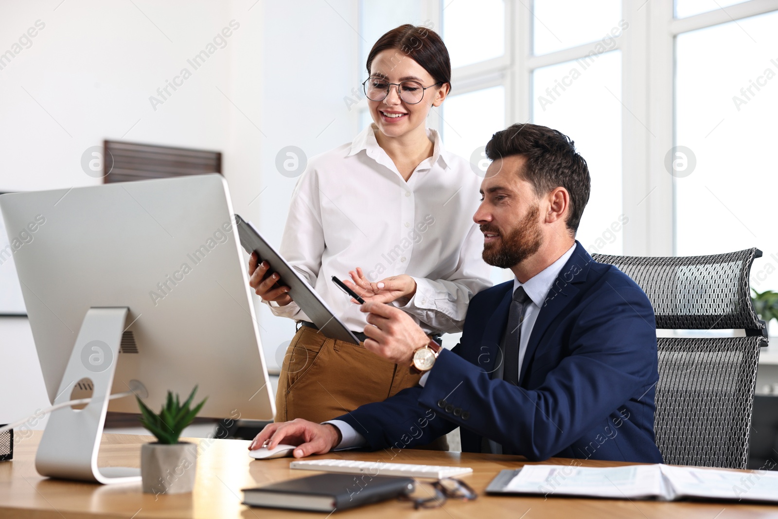 Photo of Colleagues working with computer at desk in office