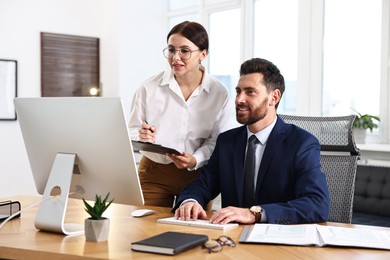 Photo of Colleagues working with computer at desk in office