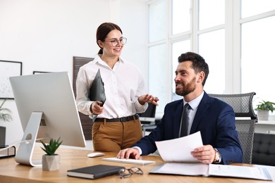 Photo of Colleagues working with computer at desk in office