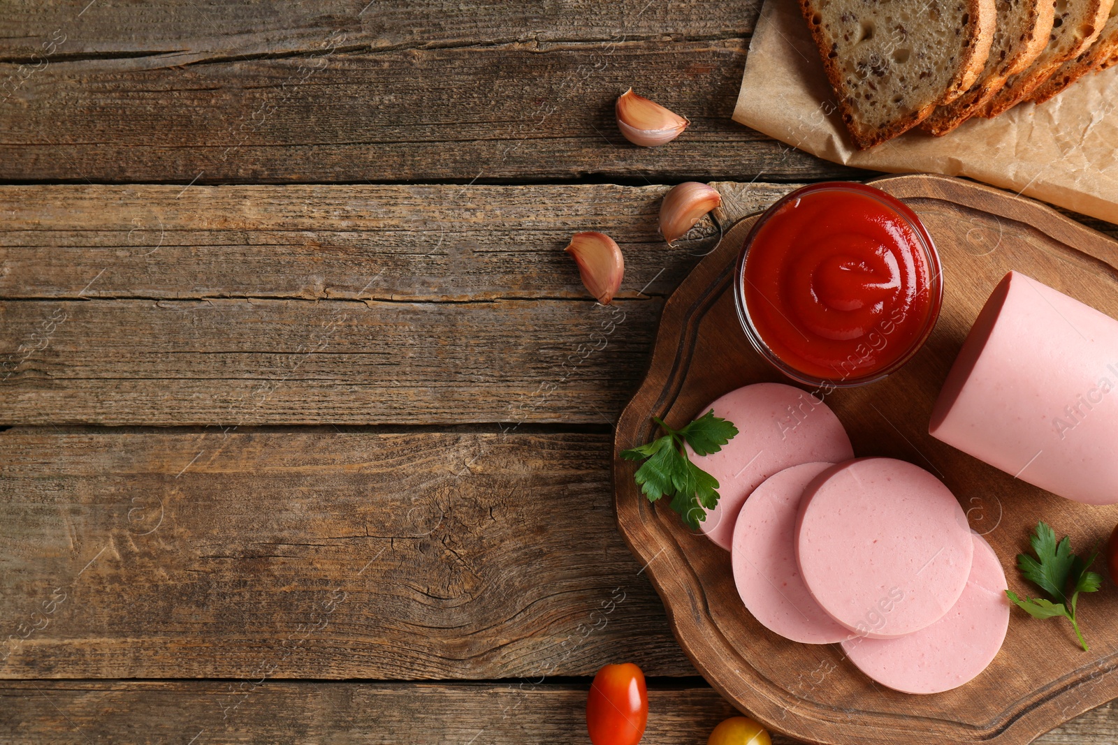 Photo of Tasty boiled sausage, ketchup, spices and bread on wooden table, top view. Space for text