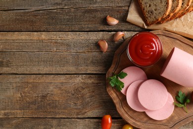 Photo of Tasty boiled sausage, ketchup, spices and bread on wooden table, top view. Space for text