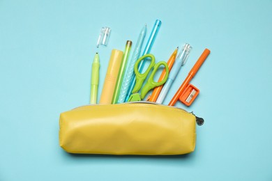 Photo of Pencil case and different stationery on light blue background, flat lay