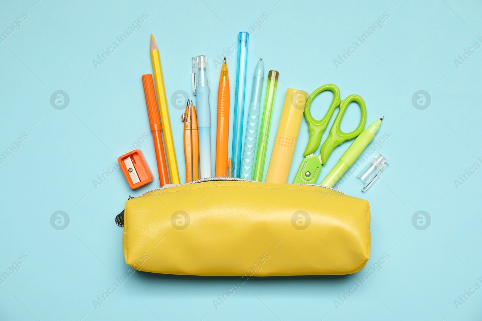 Pencil case and different stationery on light blue background, flat lay Photo of Pencil case and different stationery on light blue background, flat lay