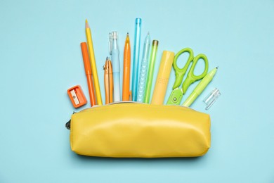 Photo of Pencil case and different stationery on light blue background, flat lay
