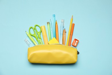 Photo of Pencil case and different stationery on light blue background, flat lay
