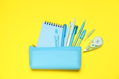 Photo of Pencil case and different stationery on yellow background, flat lay