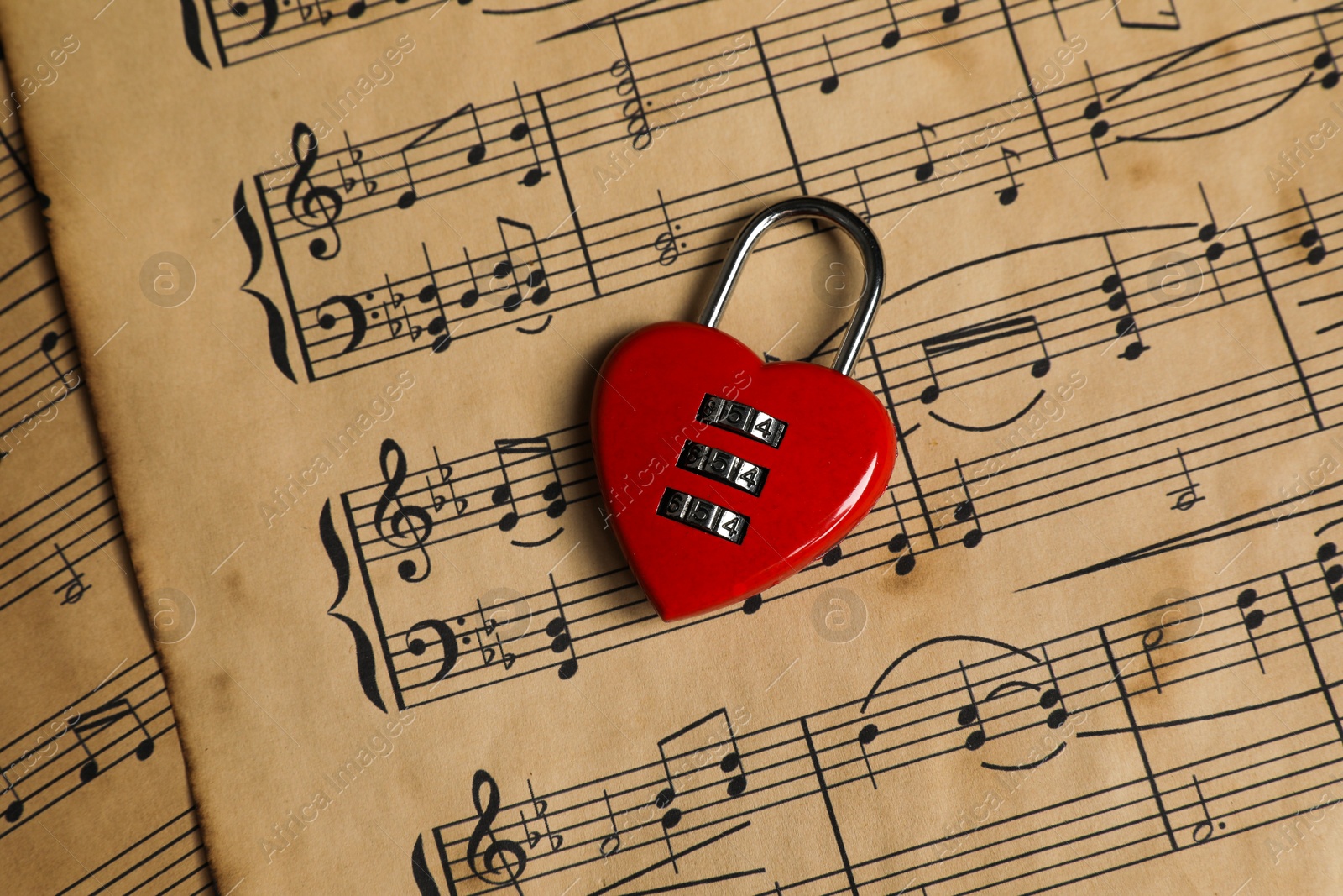 Photo of Heart shaped padlock on musical notes, closeup