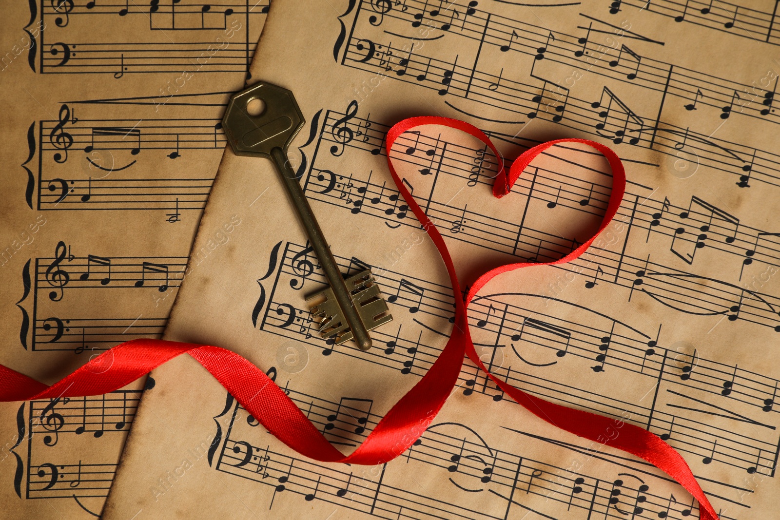 Photo of Key and heart shaped ribbon on musical notes, closeup