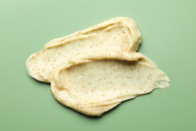 Photo of Smears of body scrub on light green background, top view