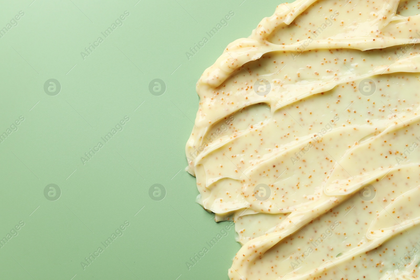 Photo of Smears of body scrub on light green background, top view. Space for text