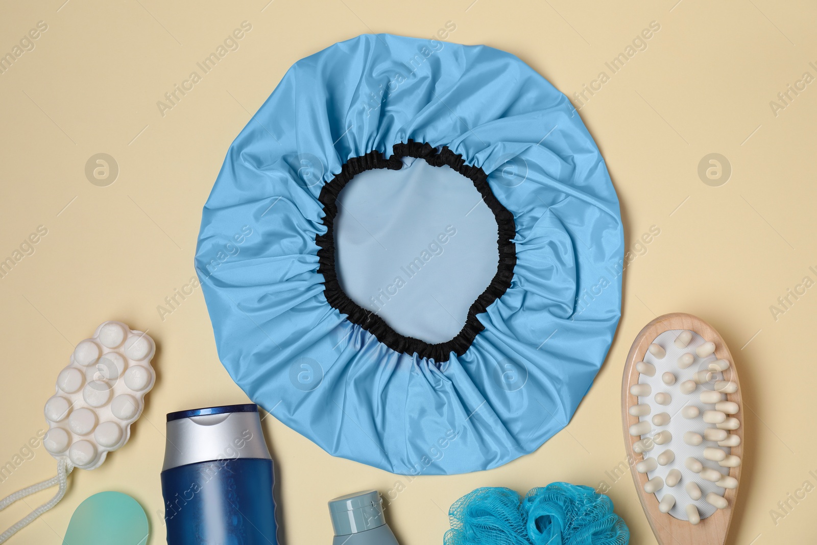 Photo of Shower cap and bath accessories on beige background, flat lay