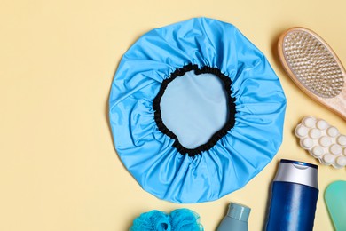 Shower cap and bath accessories on beige background, flat lay