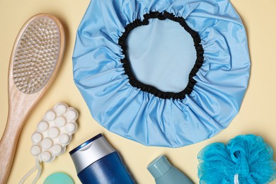 Photo of Shower cap and bath accessories on beige background, flat lay