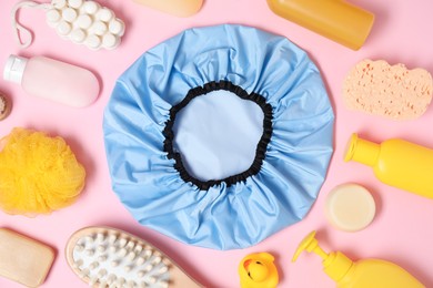 Photo of Shower cap and bath accessories on pink background, flat lay