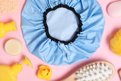 Photo of Shower cap and bath accessories on pink background, flat lay