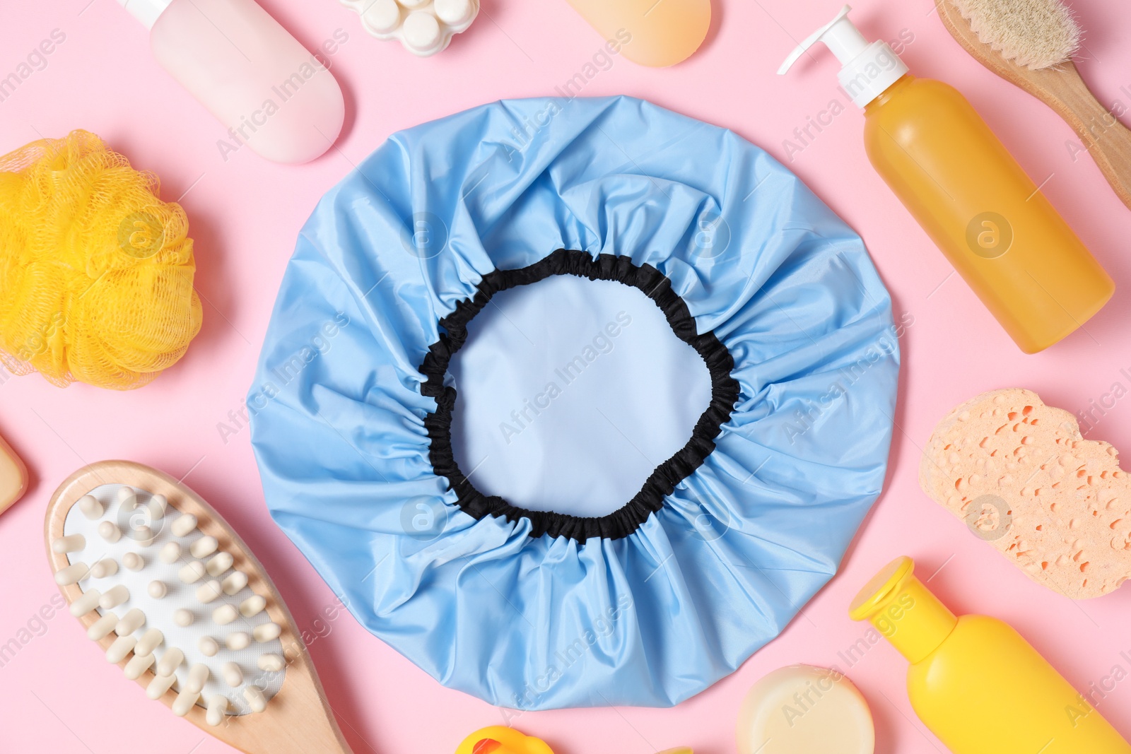 Photo of Shower cap and bath accessories on pink background, flat lay