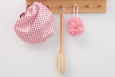 Photo of Shower cap, brush and mesh sponge on rack indoors