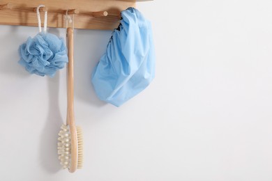 Photo of Shower cap, brush and mesh sponge on rack indoors, space for text