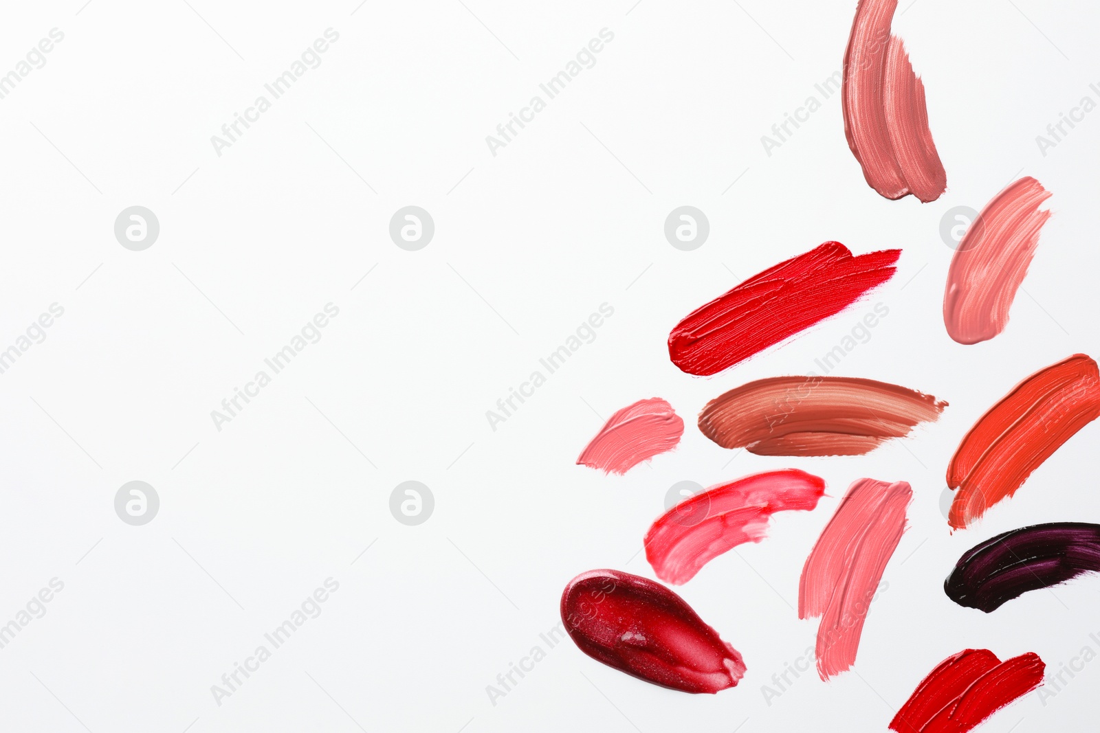 Photo of Smears of different lip products on white background, top view