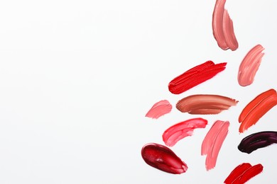 Photo of Smears of different lip products on white background, top view