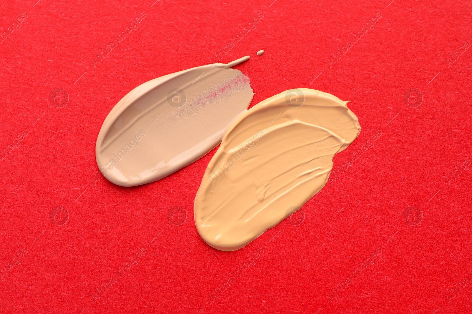 Photo of Samples of different foundations on red background, top view