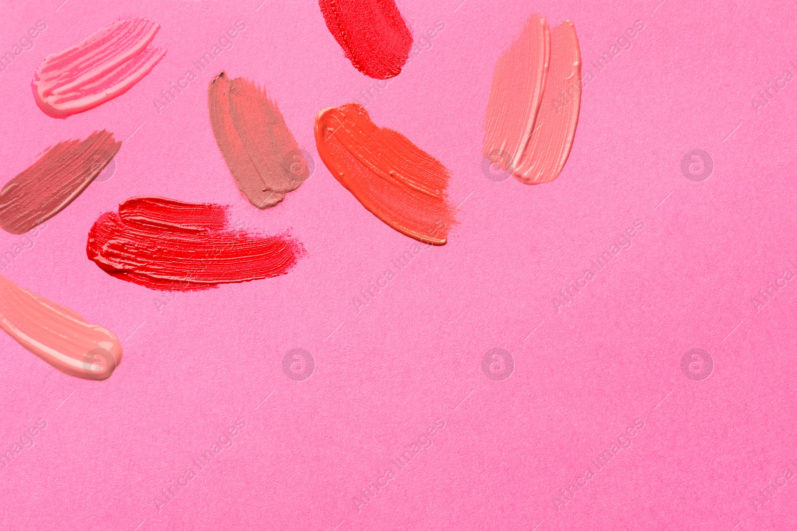 Photo of Samples of different lip products on pink background, top view. Space for text