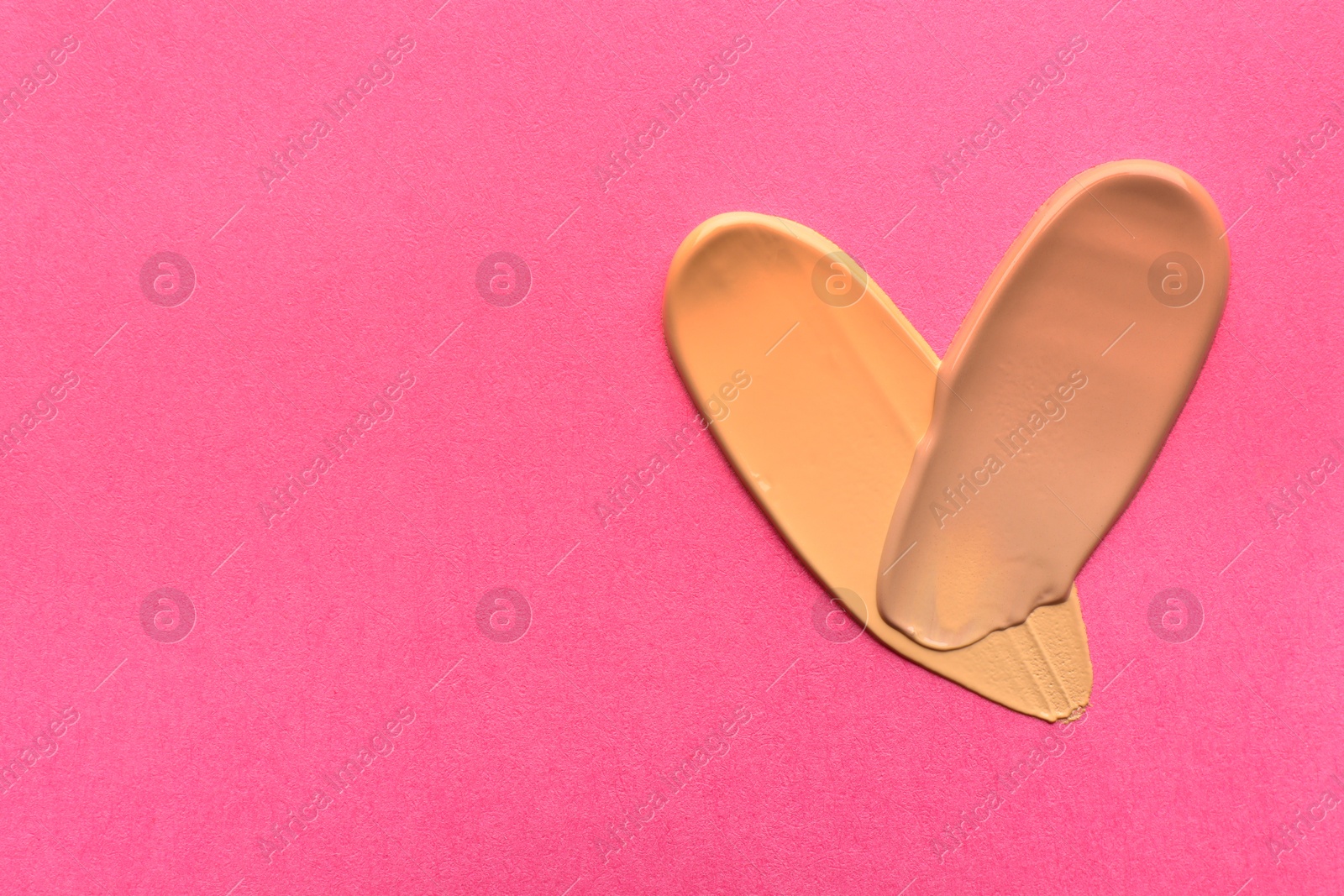 Photo of Foundation on pink background, top view with space for text. Smears of cosmetic product