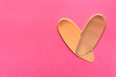 Photo of Foundation on pink background, top view with space for text. Smears of cosmetic product