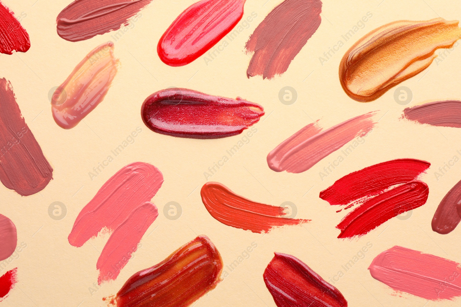 Photo of Samples of different lip products on beige background, top view