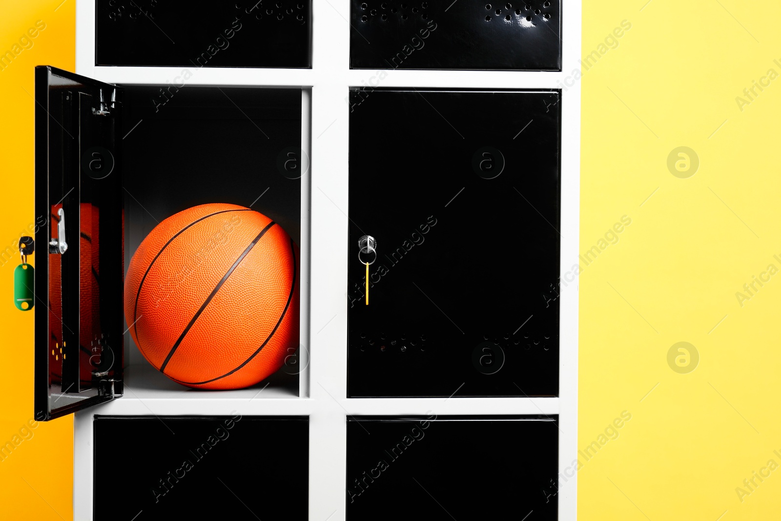 Photo of Open locker with basketball ball on orange background