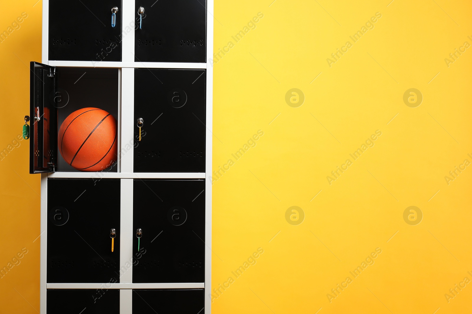 Photo of Open locker with basketball ball on orange background, space for text