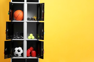 Photo of Open lockers with sport equipment on orange background, space for text