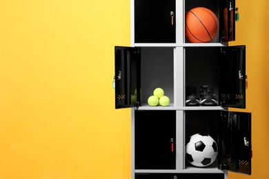 Photo of Open lockers with sport equipment on orange background, space for text