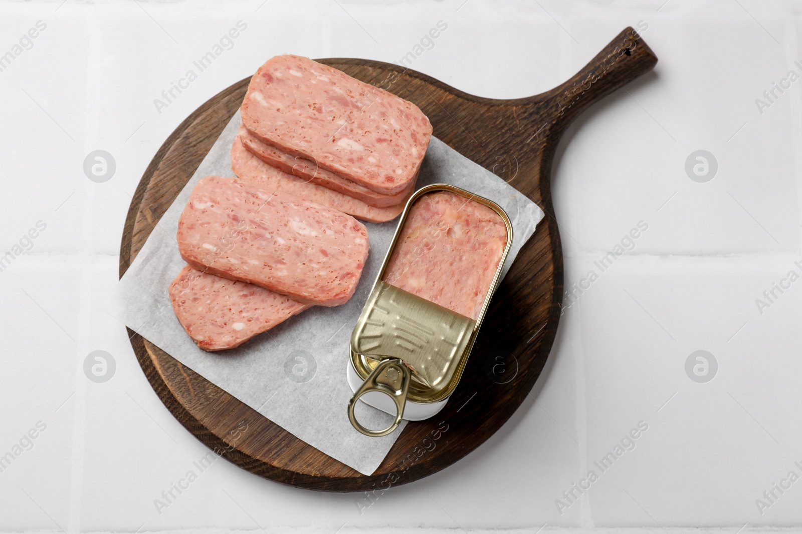 Photo of Tasty canned meat on white tiled table, top view