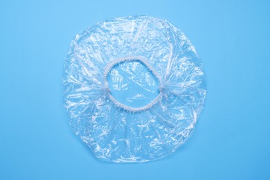 Photo of One shower cap on light blue background, top view