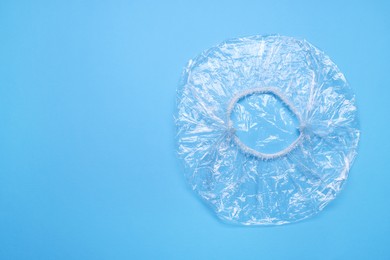 Photo of One shower cap on light blue background, top view. Space for text