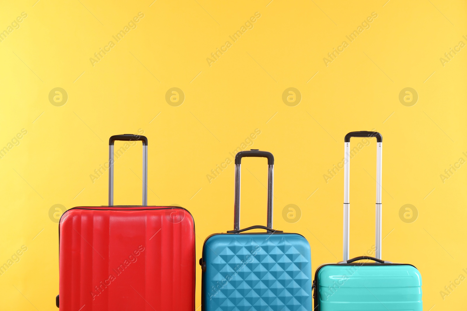 Photo of Different packed suitcases on yellow background, space for text. Travel luggage