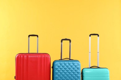 Photo of Different packed suitcases on yellow background, space for text. Travel luggage