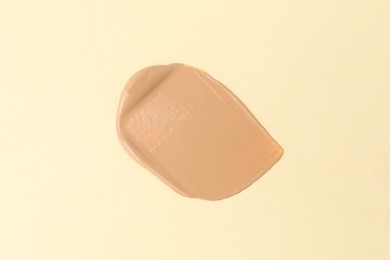 Photo of Sample of foundation on beige background, top view