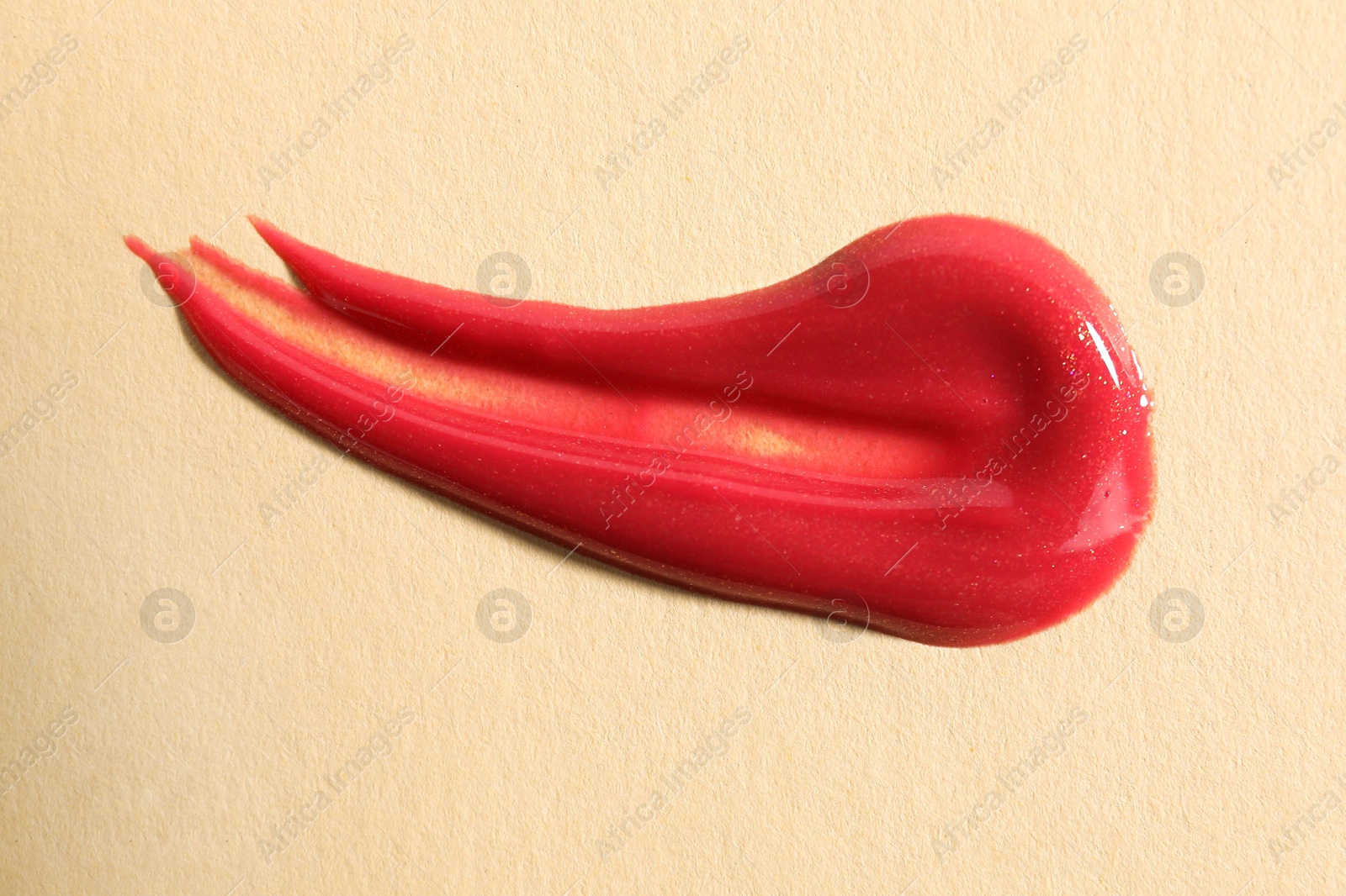 Photo of Sample of red lipgloss on beige background, top view