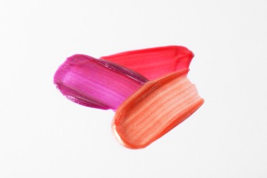 Photo of Samples of different lipglosses on light grey background, closeup