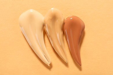 Photo of Samples of different foundations on beige background, top view