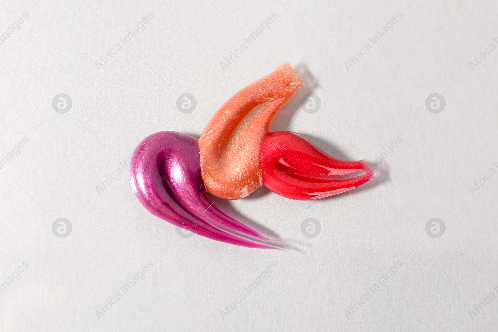 Photo of Samples of different lipglosses on light grey background, top view