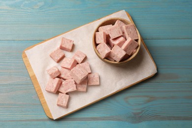 Photo of Pieces of canned meat on blue wooden table, top view