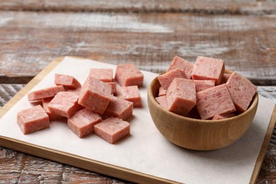 Photo of Pieces of canned meat on wooden table, closeup