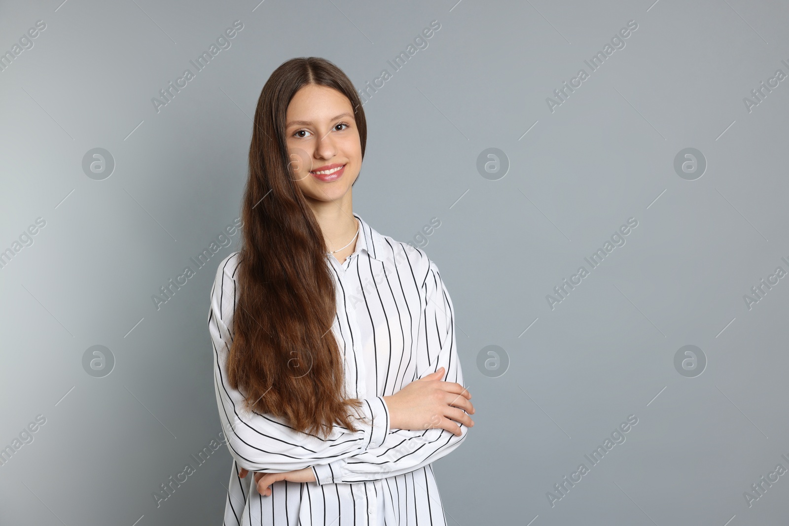 Photo of Teenage girl with long hair on light grey background. Space for text