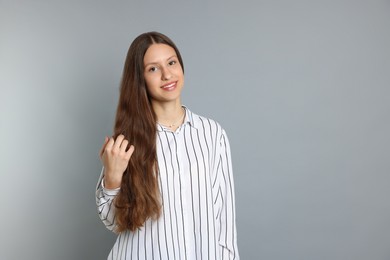 Photo of Teenage girl with long hair on light grey background. Space for text