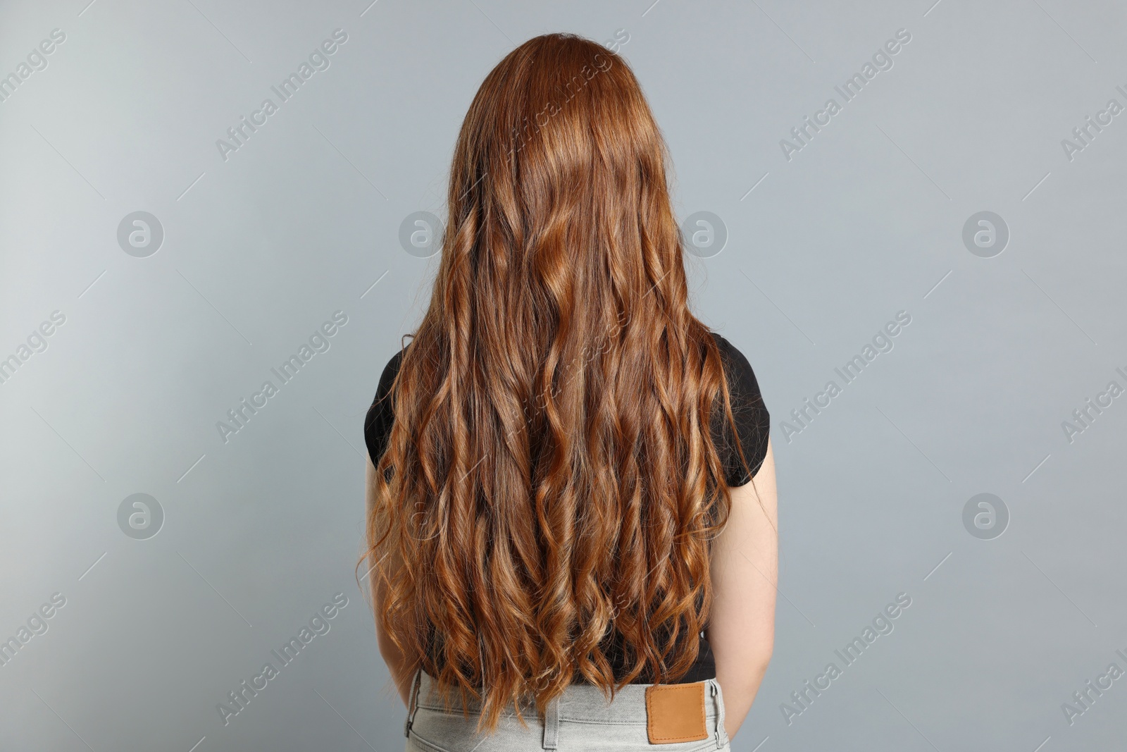 Photo of Teenage girl with healthy long hair on light grey background, back view