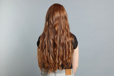 Photo of Teenage girl with healthy long hair on light grey background, back view