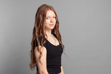 Photo of Teenage girl with long hair on light grey background. Space for text